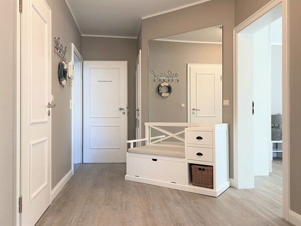 Un couloir avec un banc blanc, un miroir et une porte portant l’inscription « ANKERPLATZ ».