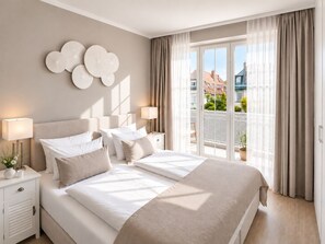 A hotel room with a large bed, two bedside tables, a lamp, and a view of the city through a balcony.