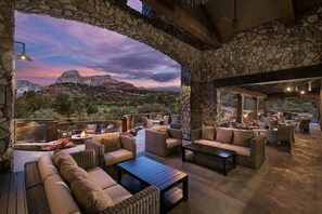 An outdoor seating area with stone walls, cushioned seating, and a view of the mountains. - Zen Retreat, Amazing Views, Minutes to Attractions (Sedona)