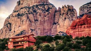 A red building with multiple floors, situated in front of a large rock formation. - Zen Retreat, Amazing Views, Minutes to Attractions (Sedona)