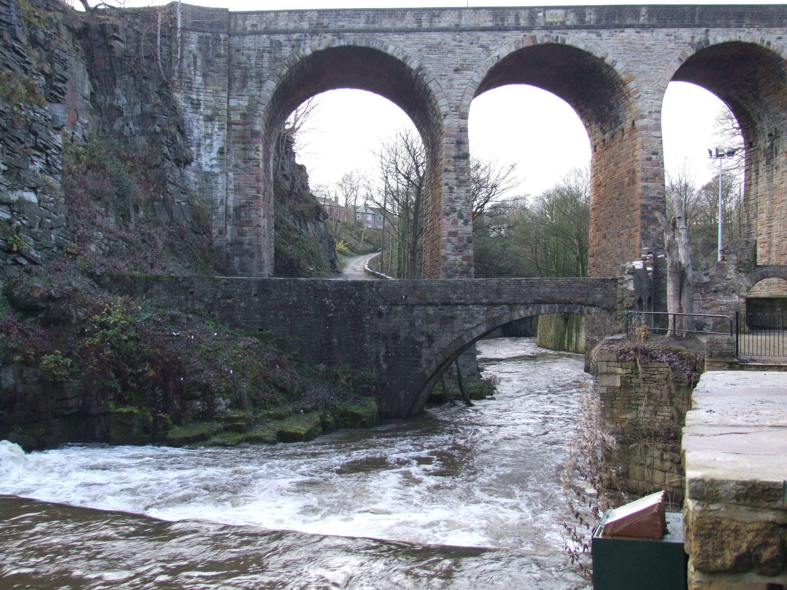 Un puente de piedra con tres arcos sobre un río caudaloso.