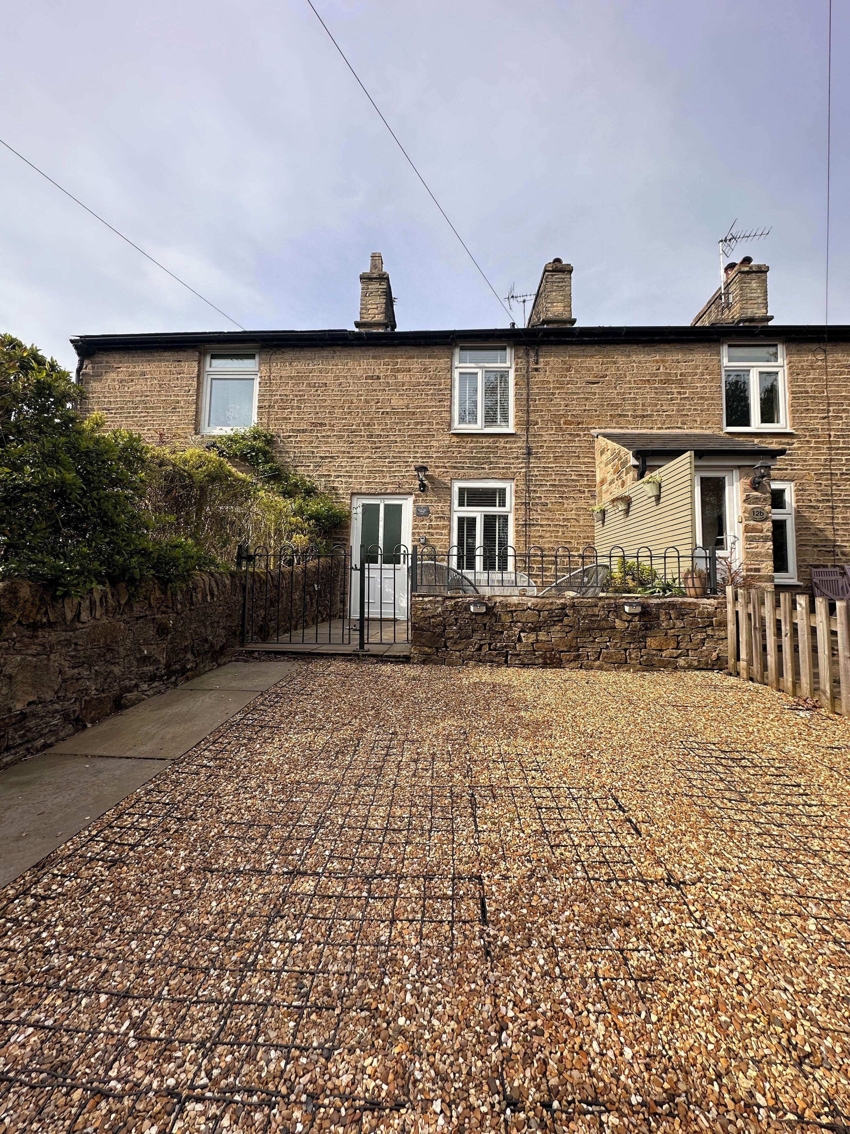 A two-story stone house with a gravel driveway.