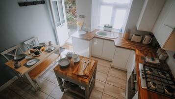Una cucina compatta con un tavolo da pranzo in legno, mobili bianchi e un piano cottura a gas.