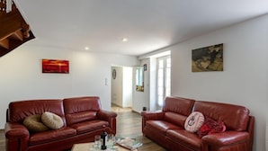 Un salon spacieux avec deux canapés en cuir rouge, une table basse en bois et un tableau accroché au mur.