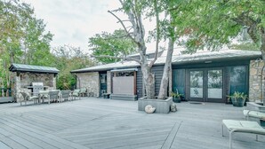 A patio with outdoor seating, a stone fireplace, and a covered area with a grill. - M'walimu 4 BR w/ Pool, Farm Stay- Flower Farm, Goats, Pigs, Disc Golf! (Glen Rose)