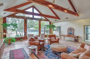 A spacious living room with a high ceiling, large windows, and a view of the outdoors. - M'walimu 4 BR w/ Pool, Farm Stay- Flower Farm, Goats, Pigs, Disc Golf! (Glen Rose)