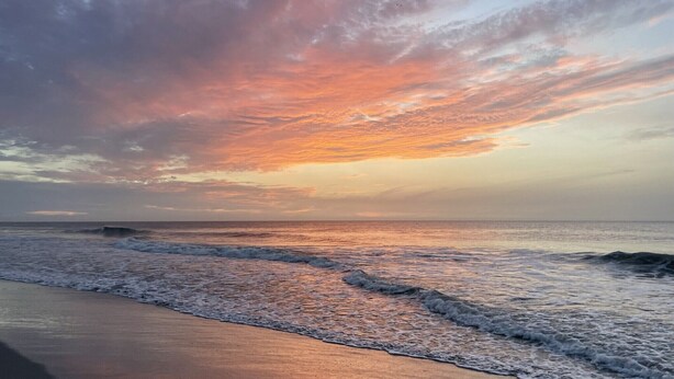 A beach with waves and a sunset sky. - Pet-friendly guest suite. Private fenced yard. 2 min walk to beach.  (Carolina Beach)