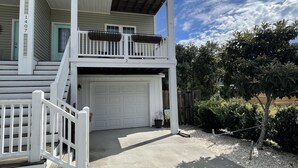 A two-story house with a garage, a covered porch, and a small balcony. - Pet-friendly guest suite. Private fenced yard. 2 min walk to beach.  (Carolina Beach)