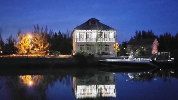 A large, illuminated building with a symmetrical facade and a reflection in the water. - The Cedar Canalfront Penthouse (Nassau)