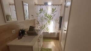 A narrow, well-lit kitchen with a white countertop, a sink, and a green rug. - The Cedar Canalfront Penthouse (Nassau)