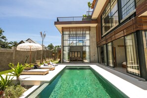 Una casa moderna con piscina, ventanas amplias y un balcón.