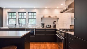 A modern kitchen with a central island, built-in appliances, and large windows. - Luxurious, Modern Walk to Water! (Orleans)