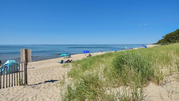 Une plage avec une clôture en bois, une tente et des gens qui se détendent.