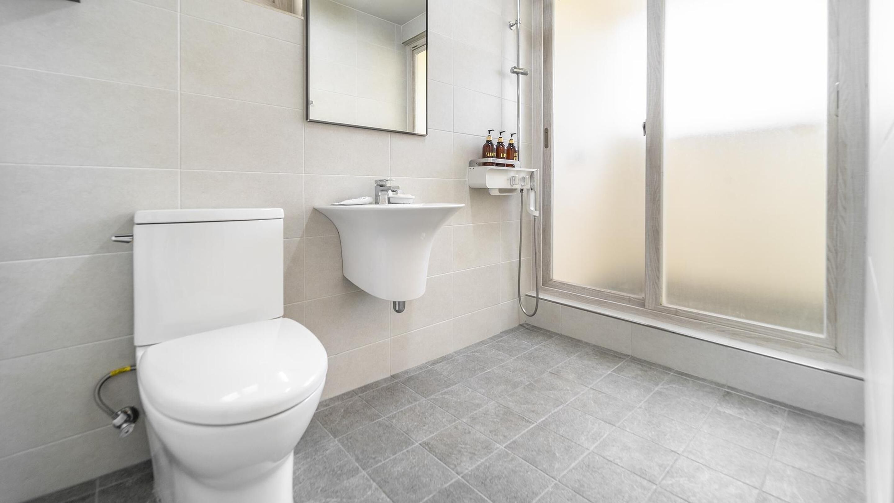 Un baño moderno con inodoro, lavamanos y ducha.