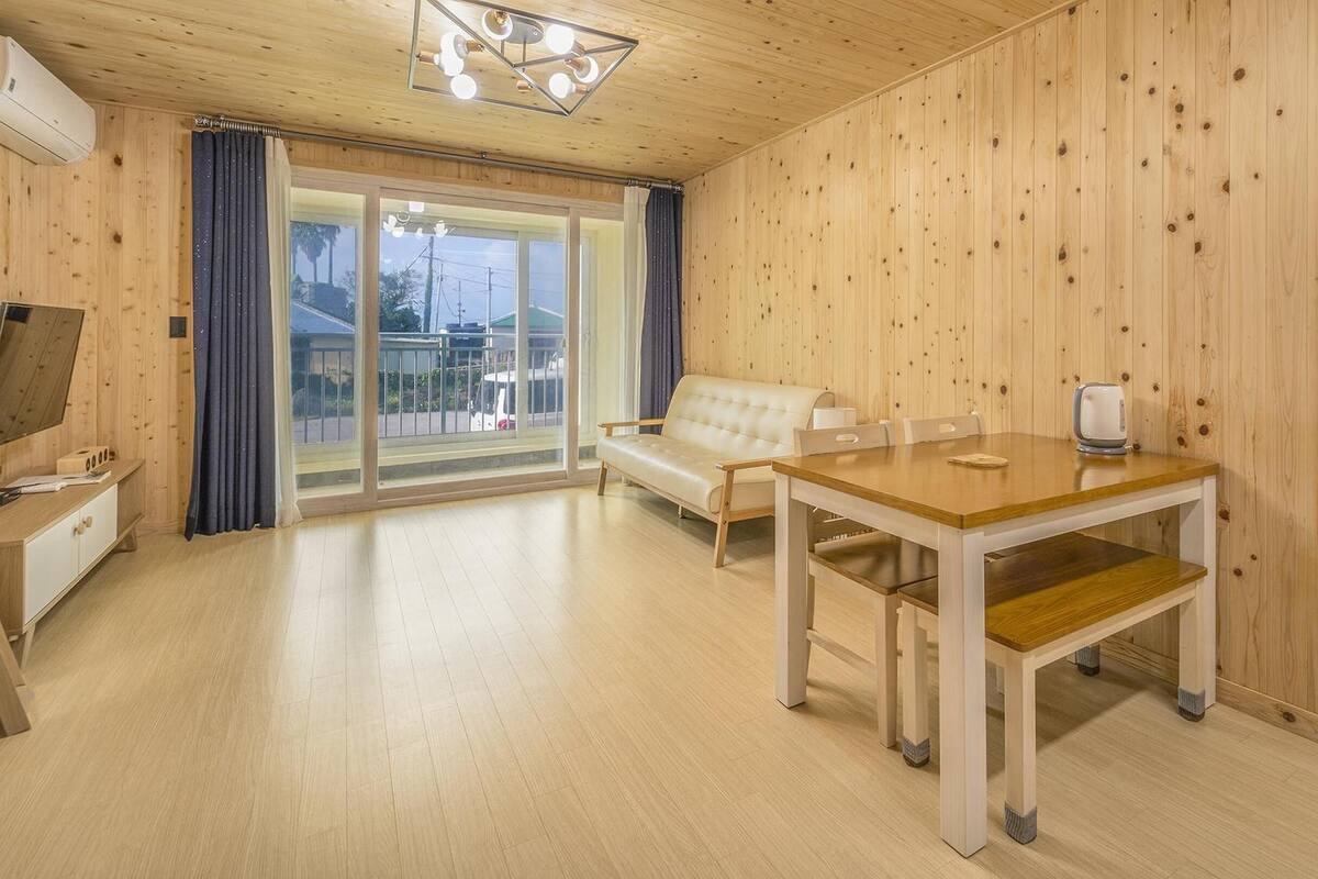 Une pièce aux murs lambrés, avec un canapé, une table et une chaise.