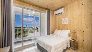 Een slaapkamer met een groot raam, een bed, een bedlampje en een airconditioning.