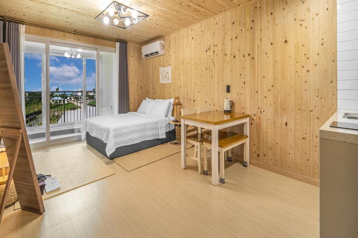Une chambre à coucher avec un lit, une table en bois et une vue sur l’extérieur.