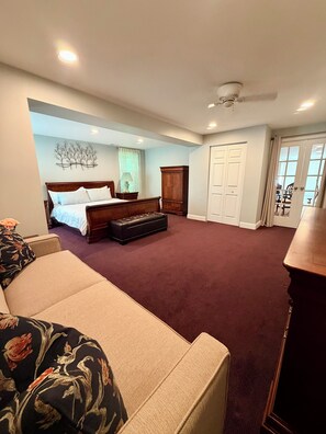 Une chambre à coucher avec un lit, une commode, un canapé et une vue sur l’extérieur.