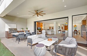 An open-plan living area with a kitchen, dining space, and a large sliding glass door leading to a patio.