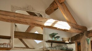 Un interior rústico con vigas de madera a la vista, una balanza antigua y frascos antiguos en estantes.