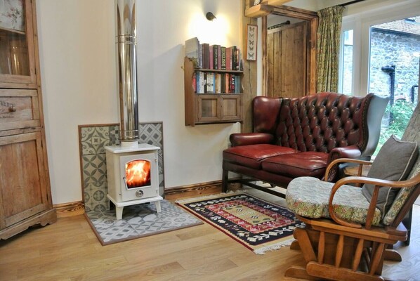 Una sala de estar acogedora con una chimenea de leña, muebles de cuero y una estantería.