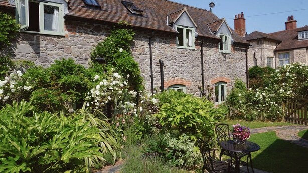 A stone house with a garden, a patio with a table and chairs, and a small shed. - Nest Holiday Hideaway Wren Cottage Stunning Area! (Church Stretton)