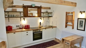 A compact kitchen with white cabinets, a wooden countertop, a red pot, a toaster, and a sink. - Nest Holiday Hideaway Wren Cottage Stunning Area! (Church Stretton)
