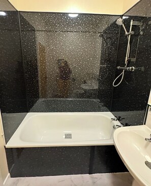 Een badkamer met een bad, douche en wastafel.