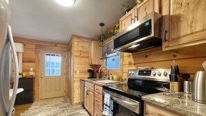 Une cuisine dotée de meubles en bois, d’un réfrigérateur en acier inoxydable, d’un four à micro-ondes, d’un four traditionnel et d’un plan de travail en granit.