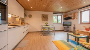 Une cuisine moderne avec des meubles blancs, un évier en acier inoxydable et un coin repas comprenant une table et des chaises.