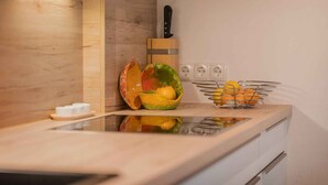 Une cuisine avec un plan de travail en bois, un saladier rempli de fruits, un bloc à couteaux et un panier à fruits.