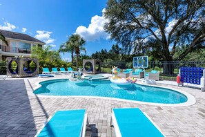 A swimming pool with lounge chairs and inflatable toys.