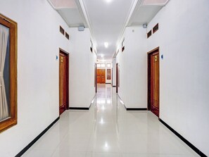 A hotel corridor with doors on both sides, a tiled floor, and a ceiling with recessed lighting. - OYO 90383 Avisha Guest House Syariah (Malang)