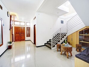 A spacious hallway with a staircase leading to an upper level. - OYO 90383 Avisha Guest House Syariah (Malang)