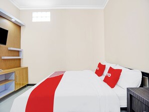 Hotellihuone, jossa on sänky, seinälle asennettu televisio, puinen kaappi ja pieni ikkuna.