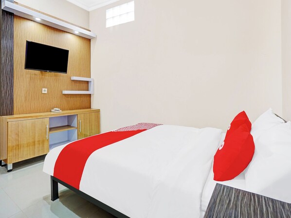 A hotel room with a bed, a desk, a television, and a window.