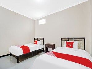 A hotel room with two beds, each with a red and white bedspread and matching pillows. The room has a modern design with a white ceiling and walls, and a small window providing natural light. - OYO 90383 Avisha Guest House Syariah (Malang)