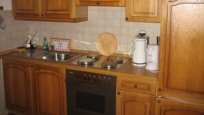 Una cocina con armarios de madera, un lavavajillas Siemens, una cafetera y una tabla de cortar de madera sobre la encimera.