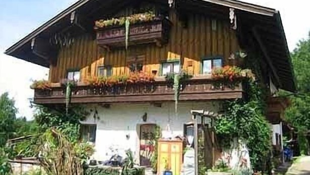 Una cabaña tradicional con fachada de madera, balcones con plantas y una entrada principal.