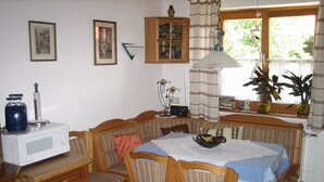 Un comedor con una mesa de madera, sillas, un microondas y un armario.