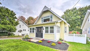 A two-story house with a front porch, a small garden with flowers, and a white picket fence. - Pet-Friendly Latham Retreat ~ 7 Mi to Albany! (Latham)