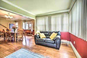 A living room with a leather sofa, wooden dining table, and chairs.