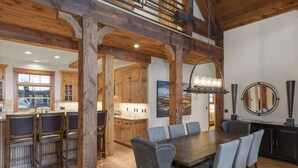 A spacious dining area with a wooden table and chairs, a kitchen in the background, and a large mirror on the wall. - Private Ski in/out Lodge! Hot Tub, 2 King En Suites, Stunning Views (Mountain Village)