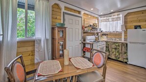 A kitchen with wooden walls, a dining table with chairs, a cabinet, and a refrigerator. - Cozy Pahoa Hideaway Near Black-Sand Beaches! (Pahoa)