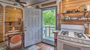 A kitchen with a stove, shelves, and a door leading to a balcony. - Cozy Pahoa Hideaway Near Black-Sand Beaches! (Pahoa)