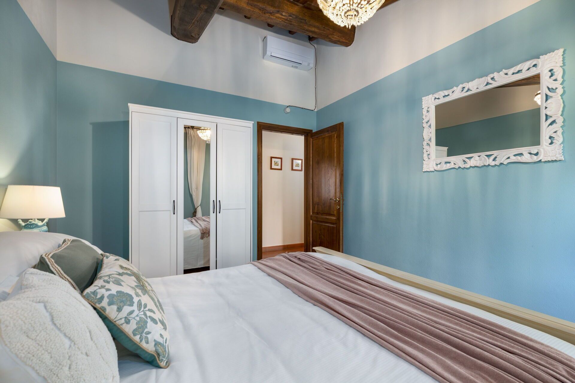 A bedroom with a bed, a nightstand, a dresser, a mirror, and a ceiling fan.