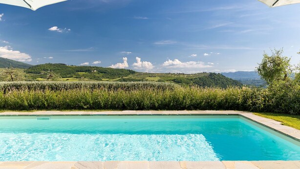 Una piscina con vistas a colinas verdes y un cielo despejado.