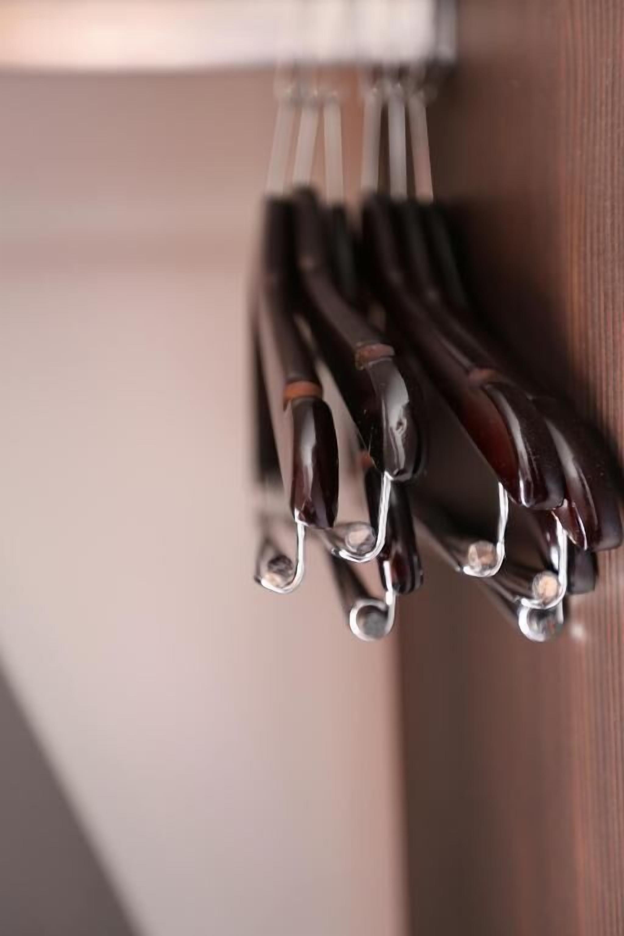 Primer plano de un juego de utensilios de cocina metálicos colgados de una superficie de madera.