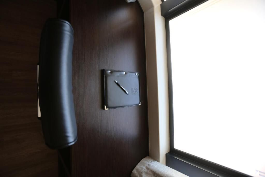 A dark wooden wall with a clock and a black object, possibly a speaker, mounted on it.