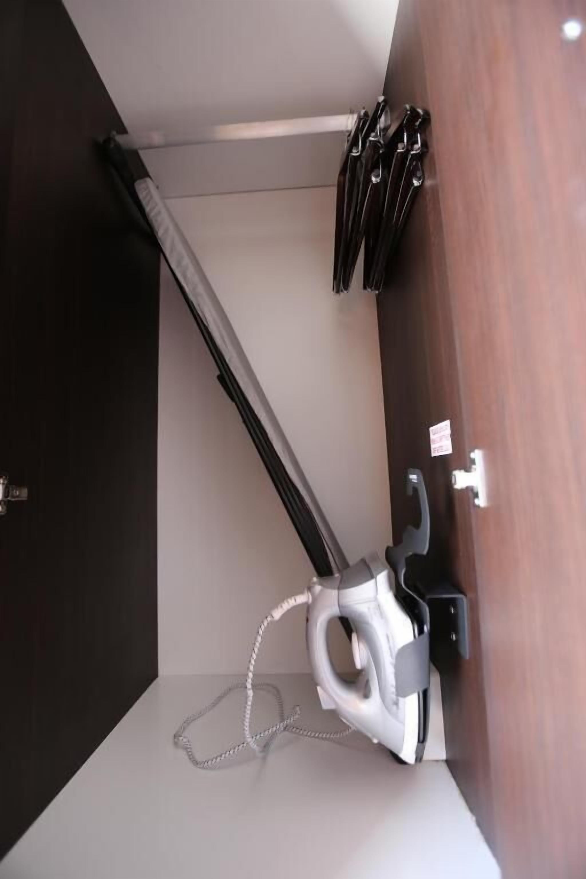A room with a vacuum cleaner, a wooden door, and a wall-mounted rack with keys.